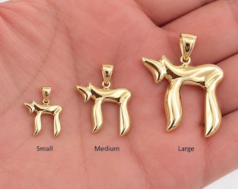 May include: Three polished gold-tone pendants in the shape of the Hebrew Chai symbol, arranged in increasing size from left to right. Each pendant features a small bail at the top. The text labels Small, Medium, and Large appear below.