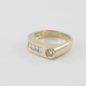 May include: A gold band ring with a single round diamond and a row of baguette diamonds.