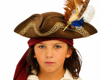 May include: A brown tricorn hat featuring gold metallic trim along the brim and a decorative cluster of feathers in shades of brown, white, and blue. The hat is worn over a dark red headscarf and a white collared shirt with a V-neckline.