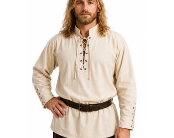May include: A long-sleeved, off-white shirt featuring a lace-up front closure with metal grommets and a stand-up collar. The sleeves include matching lace-up details at the cuffs, and the shirt is worn with a dark brown leather belt.