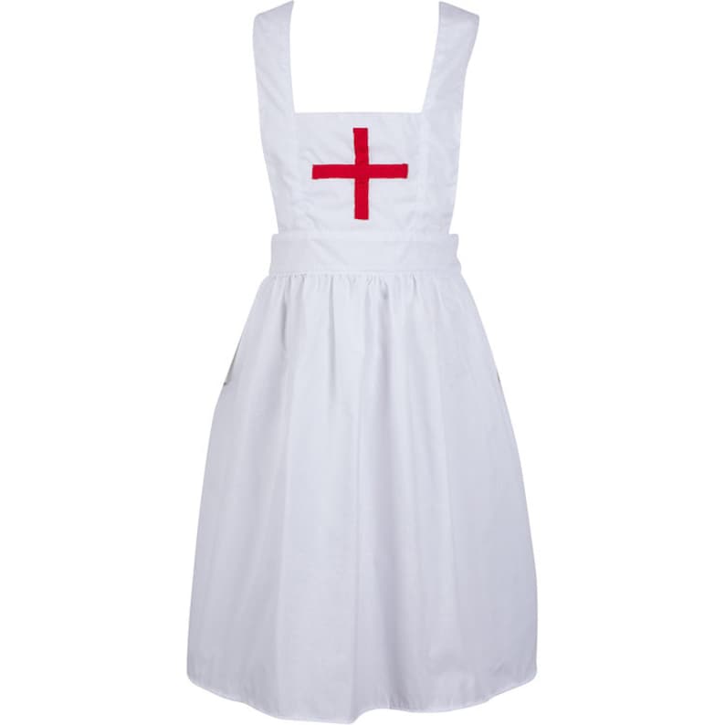 May include: A white apron featuring a square bib with a red cross emblem centred on the chest. The apron has wide shoulder straps, a fitted waistband, and a gathered skirt that falls to a knee-length hem, providing a clean and uniform appearance.