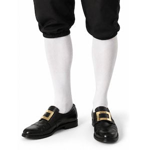 May include: A pair of black leather shoes featuring a prominent gold-toned rectangular buckle on the front, worn with solid white knee-high socks and black cropped trousers that end just below the knee with an elasticized hemline.