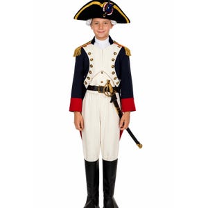 May include: A historical military-style costume featuring a navy blue jacket with gold buttons, red cuffs, and gold fringe epaulets. It includes white trousers, a white shirt, a black belt with a gold buckle, a black sword, and a black bicorne hat.