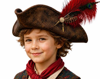 May include: A brown distressed tricorn hat featuring a large red feather, a peacock feather, and a small gold-toned metal dagger charm attached to a circular decorative pin. The hat has a weathered texture and a wide, upturned brim design.