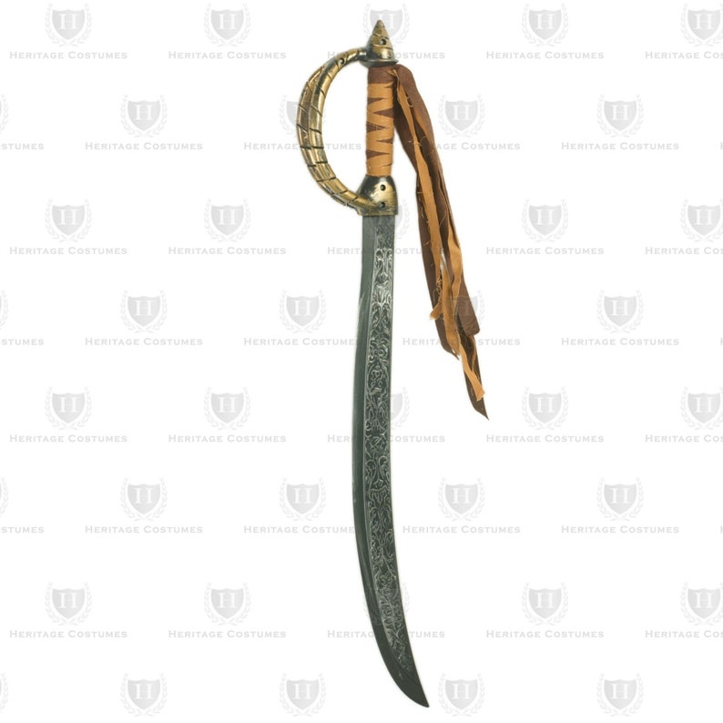 May include: A decorative saber with a curved blade and ornate detailing. The hilt is gold-colored with a brown leather grip and a loop guard. Brown leather strips hang from the hilt. The blade has an etched design. The words "HERITAGE COSTUMES" are printed on the background.