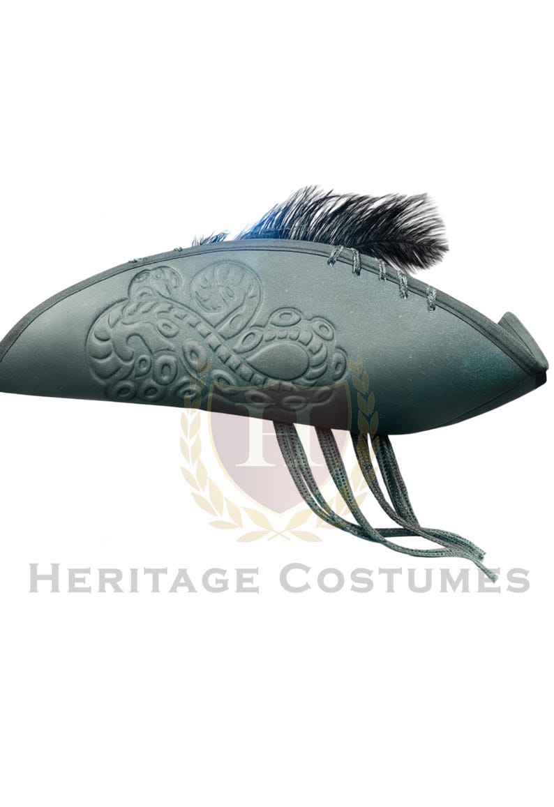 Puede incluir: Un sombrero de tres picos de color verde oscuro con un patr&oacute;n de remolinos en relieve en el lateral, una pluma negra en la parte superior y varios cordones verdes finos que cuelgan del ala. El sombrero tiene una forma estructurada y curva.