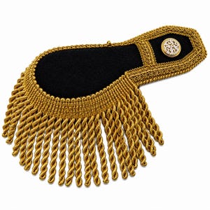 May include: A black shoulder epaulet featuring intricate gold metallic braided trim and a dense fringe of hanging gold twisted cords. The epaulet is accented with a circular gold button that has a detailed white and gold filigree pattern.