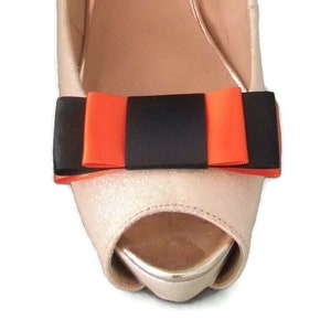 Peut inclure: Une paire de chaussures blanches avec un nœud noir et orange à l'avant.