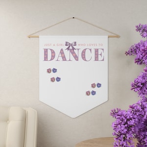 May include: A white canvas banner with a pink bow and the text "Just a girl who loves to dance". The banner has pink hearts and is decorated with small purple and blue pins.