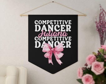 May include: Black banner with the text "COMPETITIVE DANCER Juliana COMPETITIVE DANCER" in white and pink. A pink watercolor bow is at the bottom. The banner is hung from a wooden rod.