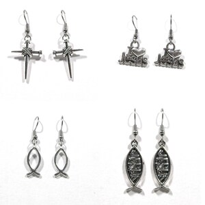 May include: A set of six silver earrings featuring religious symbols. The earrings include a cross with nails, a fish, and the words "I Love Jesus".