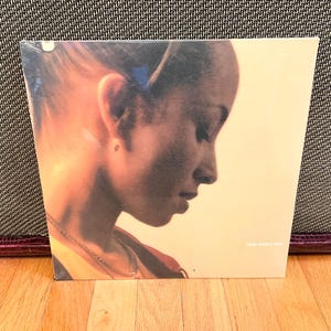 May include: A vinyl record album featuring a profile portrait of a person with a warm, golden color palette. The album cover has the text "sally shapiro heart" in a small, elegant font. The album is sealed in plastic.