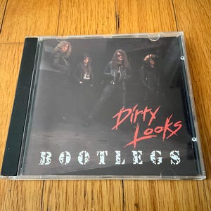 May include: A music CD in a clear plastic jewel case featuring the album cover for Dirty Looks Bootlegs. The cover art displays a black and white photograph of a four-piece band in leather jackets, with the red text Dirty Looks and white text BOOTLEGS.