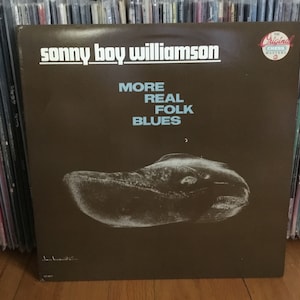 May include: A brown vinyl record album cover with the title "Sonny Boy Williamson - More Real Folk Blues" in white text. The album cover features a black and white image of a fish.