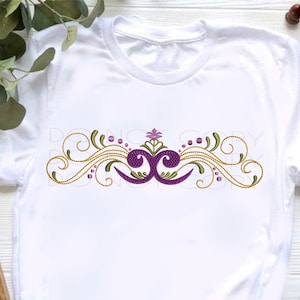 Pode incluir: Camiseta branca com um design bordado em roxo e dourado com um motivo floral e redemoinhos.