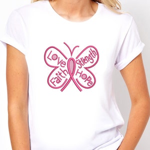 May include: White t-shirt with a pink butterfly design. The butterfly is made up of the words "Love", "Faith", "Hope", and "Strength" and a pink ribbon in the center.