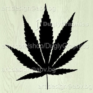 Puede incluir: Silueta negra de una hoja de marihuana sobre un fondo de madera claro.