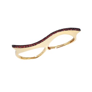 Puede incluir: Anillo de doble dedo de oro con un diseño de onda y piedras preciosas rojas.