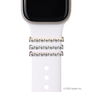 May include: Three Apple Watch band attachments with a row of clear rhinestones. The attachments are in gold, silver, and rose gold.