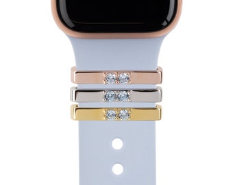 May include: Three Apple Watch bands with two clear rhinestones on each. The bands are rose gold, silver, and gold.