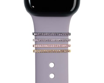 May include: Four different colored Apple Watch bands with a row of clear rhinestones. The bands are black, silver, rose gold, and gold.