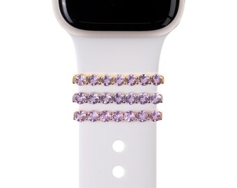 May include: Three gold bands with rows of light purple rhinestones, designed to be worn on a watch band.
