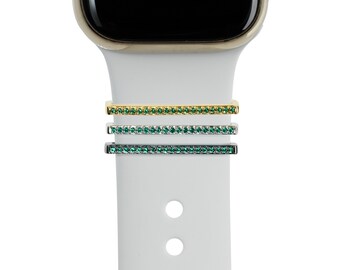 May include: Three watch band attachments with a row of green rhinestones. The attachments are gold, silver, and black.