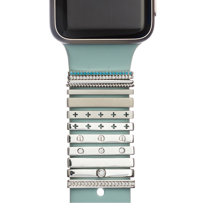 May include: A light blue silicone watch band with a variety of silver and turquoise metal bands attached to it. The bands have different designs, including a row of turquoise stones, a row of diamonds, a row of crosses, and a row of dots.