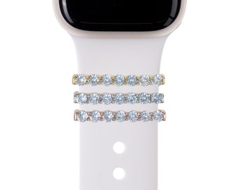 May include: Three Apple Watch bands with a row of clear cubic zirconia stones. The bands are gold, silver, and rose gold.