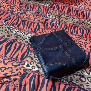 Pu&ograve; includere: Una borsa a tracolla in pelle nera con patchwork e una catena argentata. La borsa ha un design unico con pi&ugrave; pannelli cuciti.