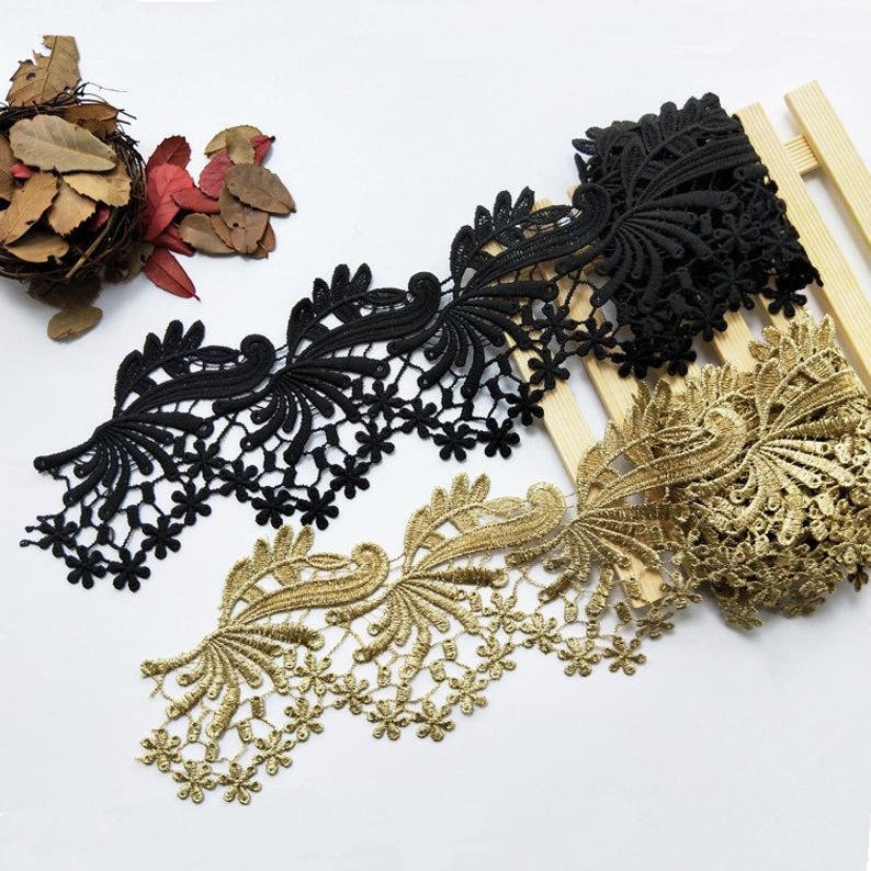 May include: Two pieces of black and gold lace trim with a floral design. The lace is delicate and intricate, with a scalloped edge.
