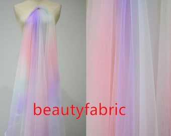 May include: A sheer fabric with a gradient of pink, purple, and white colors. The fabric is soft and delicate, and it would be perfect for making dresses, skirts, or other garments.