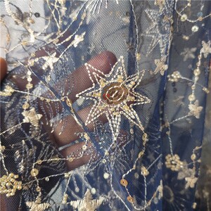May include: Blue mesh fabric with gold embroidered stars and sequins.