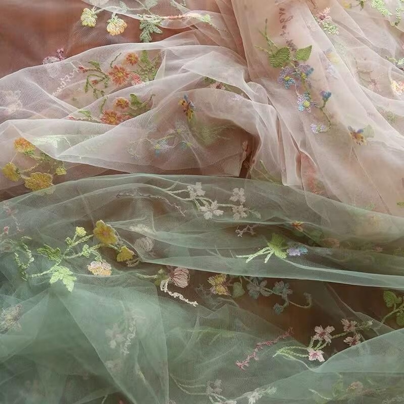 May include: Two layers of sheer fabric with floral embroidery. The top layer is a light pink color and the bottom layer is a light green color.