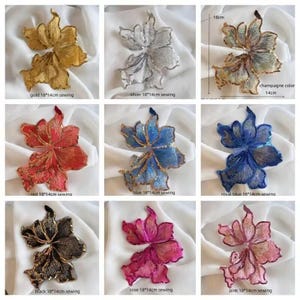 May include: A collection of nine floral-shaped sewing appliques in various colors including gold, silver, champagne, red, blue, royal blue, black, rose, and pink. Each piece measures 18 cm by 14 cm and features intricate embroidery and sequin details.