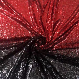 May include: A close-up of a fabric with a gradient effect, transitioning from red at the top to black at the bottom. The fabric is covered in small, reflective sequins, creating a shimmering effect. The material is likely used for decorative purposes.