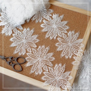 May include: White lace trim with a delicate floral design. The trim features a repeating pattern of small flowers with intricate details. The lace is soft and delicate, making it perfect for adding a touch of elegance to any project.