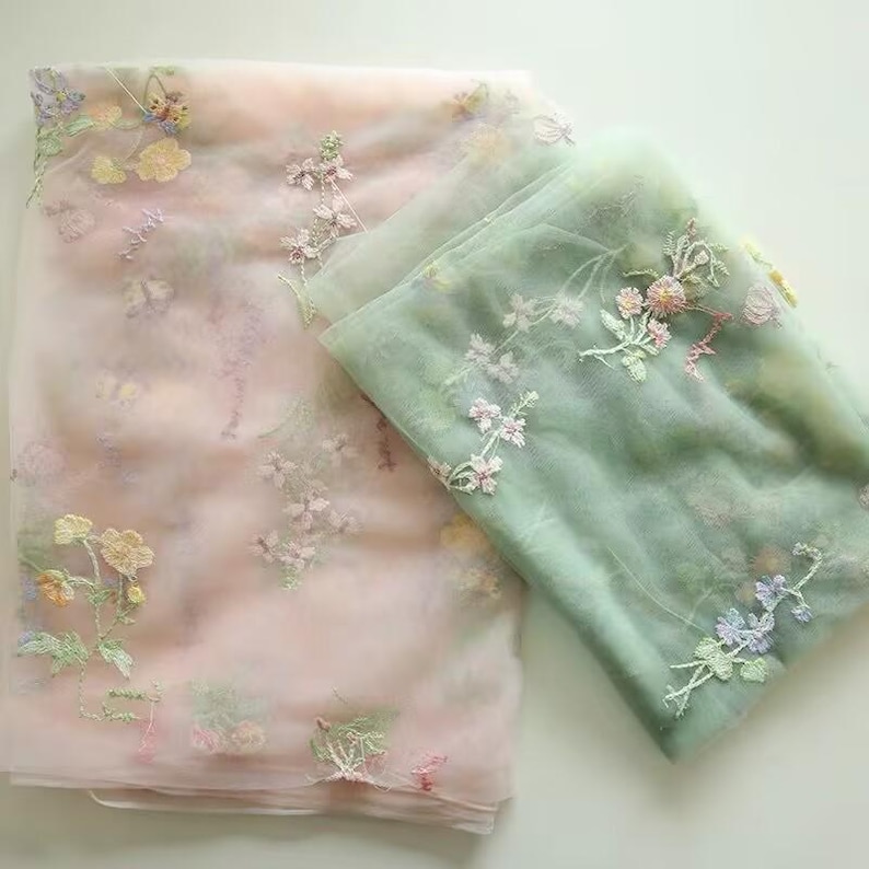 May include: Two layers of sheer fabric with floral embroidery. The top layer is pink with white and light pink flowers. The bottom layer is green with white and light green flowers.