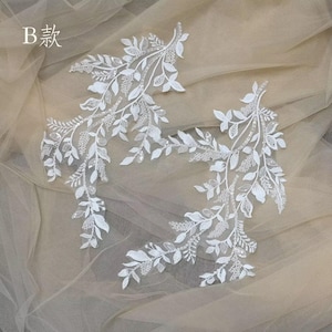 Puede incluir: Tres aplicaciones de encaje blanco en forma de ramas con hojas. Las aplicaciones están sobre un fondo de tul blanco. El texto "B 款" está en la esquina superior izquierda de la imagen.