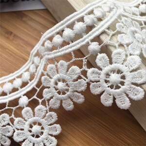 May include: White lace trim with a scalloped edge and a repeating pattern of small flowers and circles.