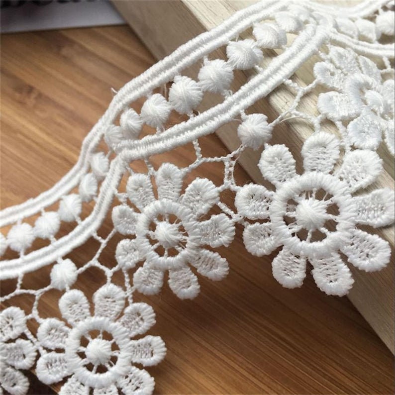 May include: White lace trim with a scalloped edge and a repeating pattern of small flowers and circles.