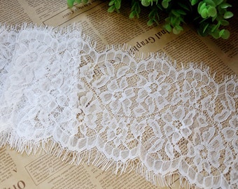 May include: White lace trim with a delicate floral pattern and a frayed edge.