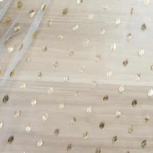 Puede incluir: Tela de tul blanco con lunares dorados. La tela es transparente y tiene una textura delicada.