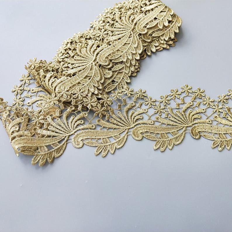May include: Gold lace trim with a delicate floral pattern. The lace is about 2 inches wide and has a scalloped edge.