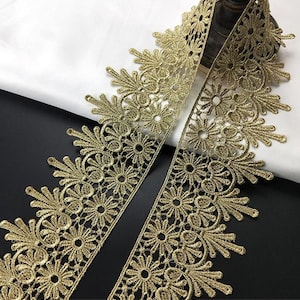 Puede incluir: Borde de encaje dorado con un delicado patrón floral. El encaje tiene un borde festoneado y es perfecto para agregar un toque de elegancia a cualquier proyecto.