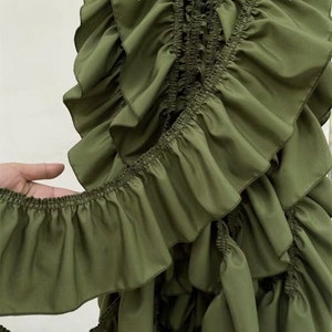 May include: A green ruffled fabric with multiple layers. The fabric is soft and has a delicate texture.