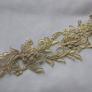 May include: Gold floral lace trim with a delicate design featuring intricate swirls and flowers. This trim is perfect for adding a touch of elegance to any project.