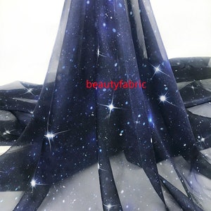 May include: A sheer blue fabric with a galaxy print featuring white stars. The fabric is lightweight and translucent, ideal for creating flowing garments or accessories.