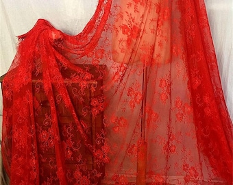 May include: Red lace fabric with a floral pattern. The lace has a scalloped edge.