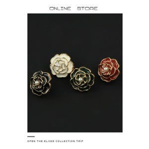 May include: Four rose-shaped earrings in black, white, green, and red with gold trim and a pearl center. The earrings are displayed on a black background. Text at the top reads "ONLINE STORE" and at the bottom "OPEN THE ELVES COLLECTION TRIP".